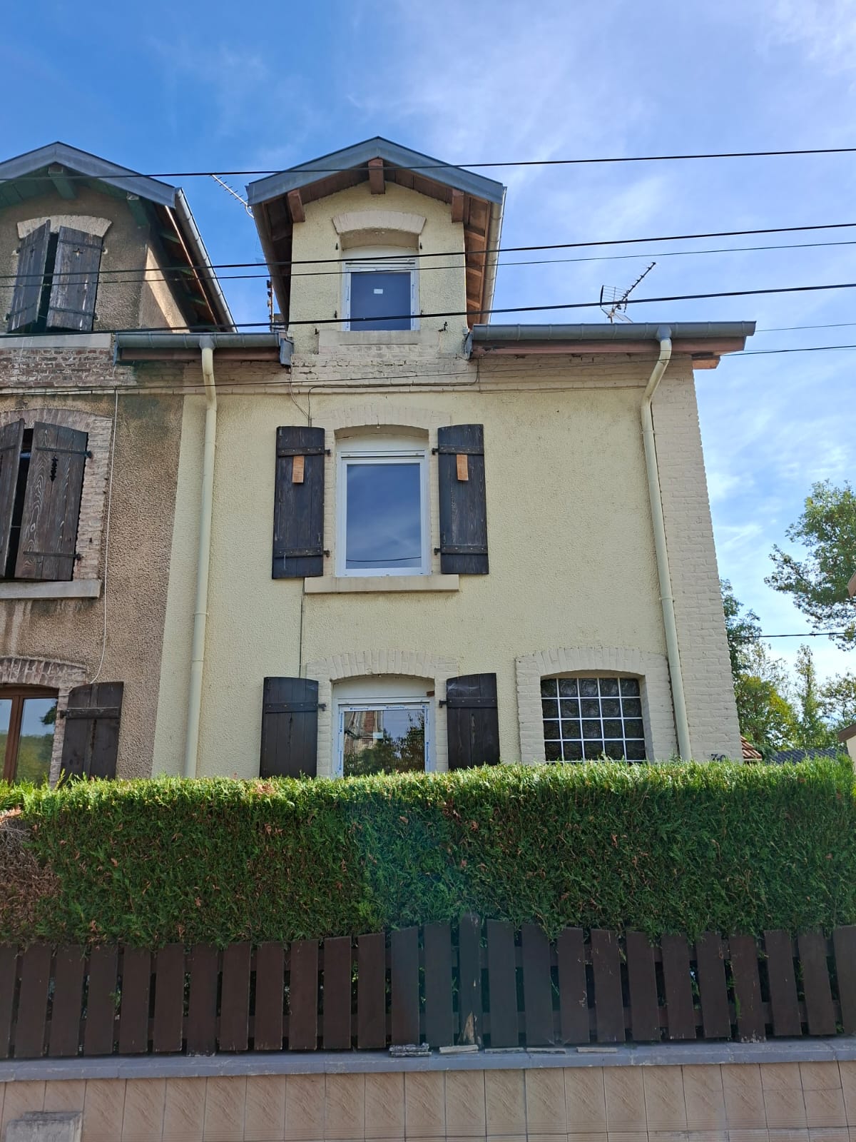 Façade après les travaux : nouvelles fenêtres blanches et volets roulants.